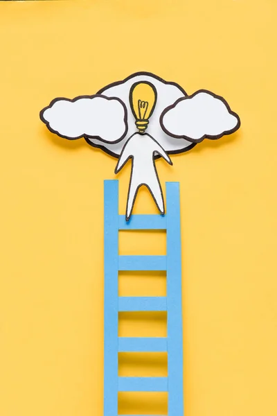 段ボール電球頭のアイデア コンセプト黄色背景にはしごを登る男のトップ ビュー — ストック写真