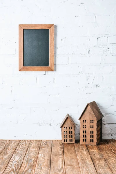 白いレンガの壁に茶色の空白枠木製テーブルの上の素朴な家のモデルに — ストック写真
