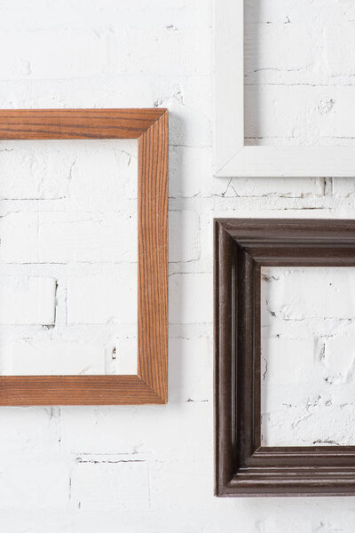 Деревенские разноцветные пустые рамы, висящие на стене из белого кирпича
