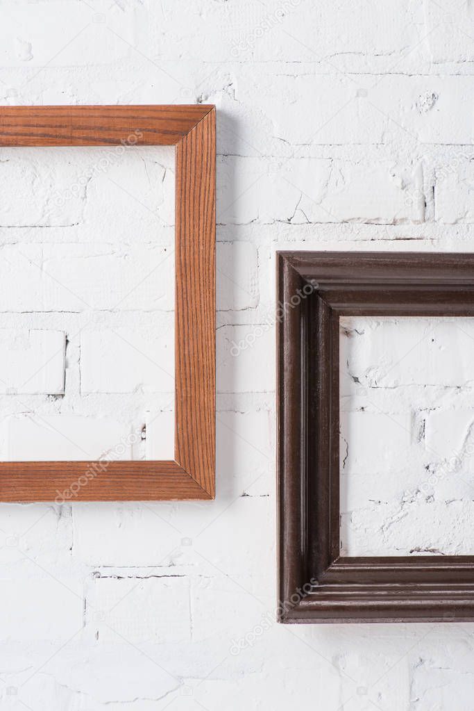 brown and black empty frames hanging on white brick wall