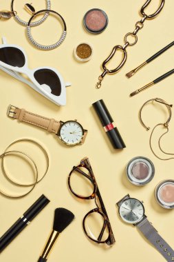Top view of watches, lipstick, glasses, sunglasses, eyeshadow, blush, cosmetic brushes, bracelets, earrings and mascara  clipart