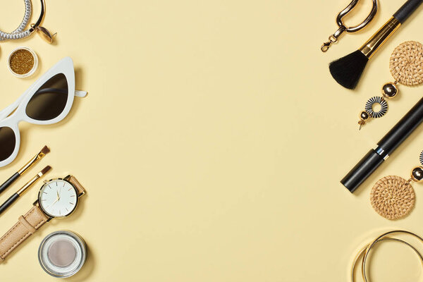 Top view of watches, sunglasses, eyeshadow, cosmetic brushes, bracelets, earrings and mascara 