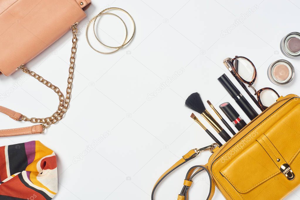 Bags, scarf, glasses, cosmetic brushes, lipstick, eyeshadow and bracelets on white background
