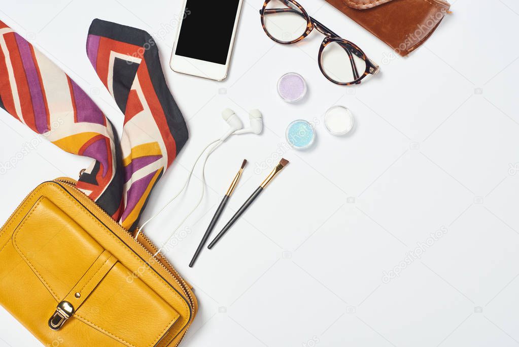 Bag, scarf, glasses, cosmetic brushes, case, earphones, eyeshadow and smartphone on white background