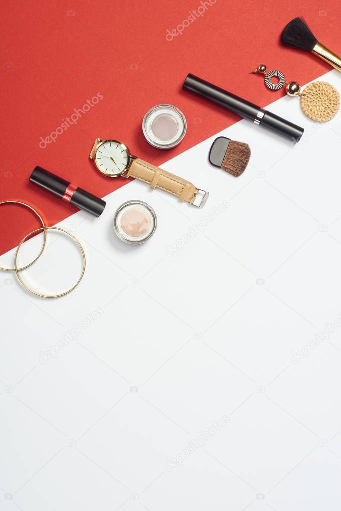 Flat lay with mascara, watch, lipstick, bracelets, eyeshadow, cosmetic brushes and earring