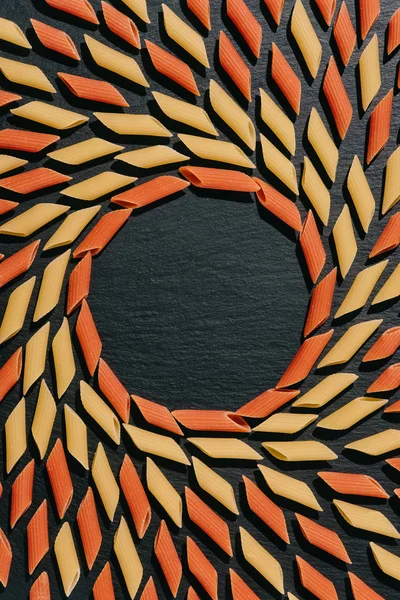 Top view of circle frame made of pasta on black surface — Stock Photo