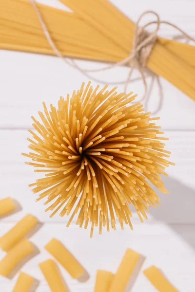 Вид сверху на кучу сырых спагетти на белом деревянном столе — стоковое фото