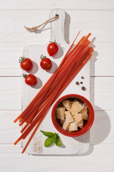Vista superior de vários alimentos italianos com espaguete vermelho na placa de corte de madeira branca — Fotografia de Stock