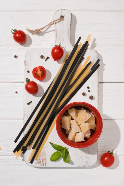 Vista dall'alto di vari piatti italiani con spaghetti bianchi e neri su tagliere in legno bianco — Foto stock