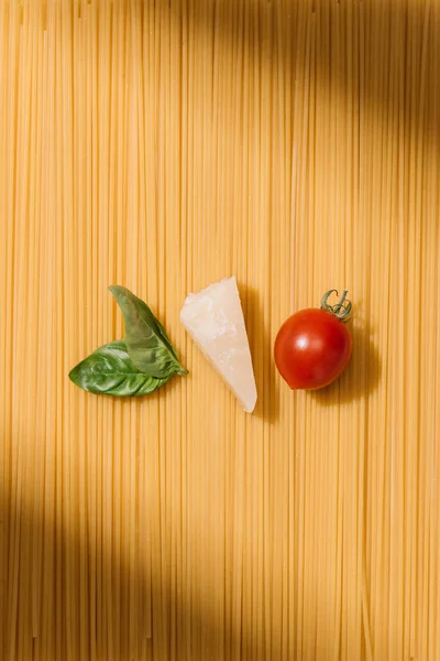 Вид сверху на базилик, сыр и помидоры, лежащие на спагетти — стоковое фото