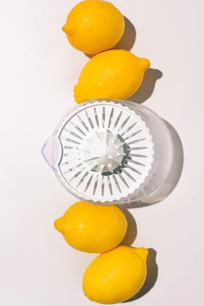 Top view of squeezer between lemons on white table — Stock Photo