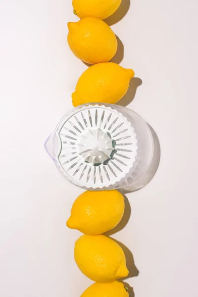 Vista elevada del exprimidor entre limones en la mesa blanca - foto de stock