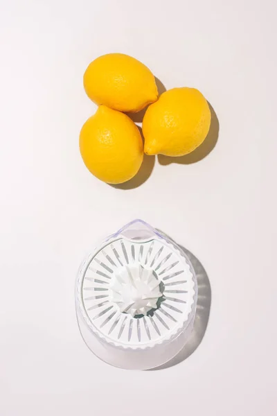 Vista superior de exprimidor y limones sobre mesa blanca - foto de stock