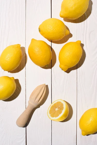 Vista sopraelevata di limoni e spremiagrumi in legno su tavolo in legno — Foto stock