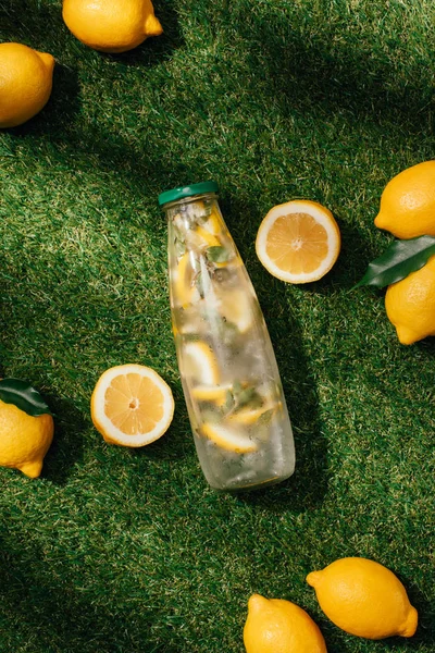 Elevated view of bottle of lemonade and lemons on green lawn — Stock Photo