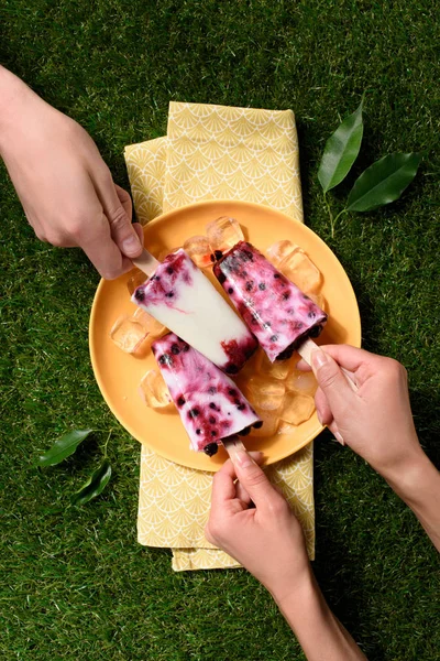 Prendre à la main délicieuse crème glacée sur fond d'herbe verte — Photo de stock