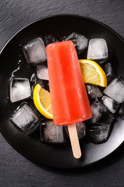 Deliciosas paletas rojas sobre cubitos de hielo con limón - foto de stock