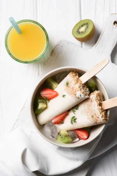 Gelo de frutas aparece com morango e kiwi na tigela na mesa com suco de laranja — Fotografia de Stock