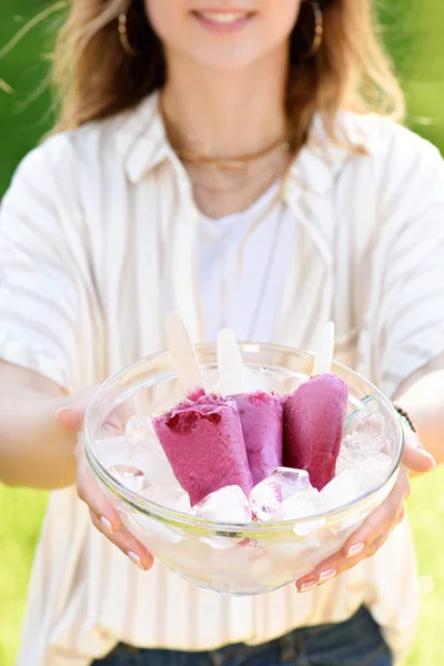 Woman holding bowl with berry popsicles and ice cubes — Stock Photo