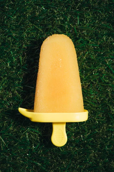 Fruit jaune sucré Popsicle sur fond d'herbe verte — Photo de stock
