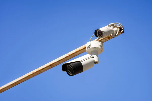 Close up view of security cameras on pole against bright blue sky — Stock Photo