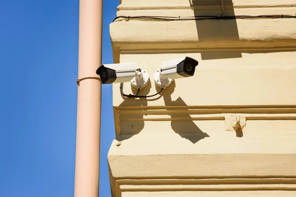 Close up view of security cameras on yellow building facade — Stock Photo