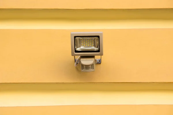 Close up view of spotlight lamp on yellow building facade — Stock Photo