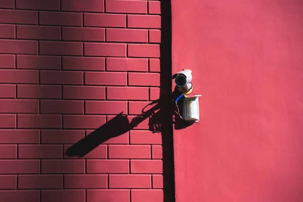 Vista de cerca de la cámara de seguridad en la fachada del edificio rosa a la luz del sol - foto de stock
