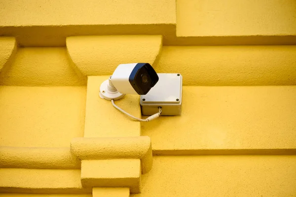 Vista de perto da câmera de segurança na fachada do edifício amarelo — Fotografia de Stock