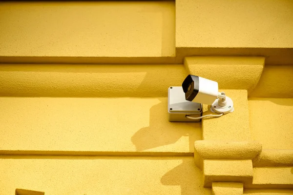Close up view of security camera on yellow building facade — Stock Photo