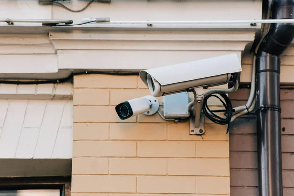 Close up view of security cameras on orange colored building facade — Stock Photo