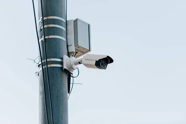 Vista de cerca de la cámara de seguridad en el poste de la calle con el cielo azul en el fondo - foto de stock