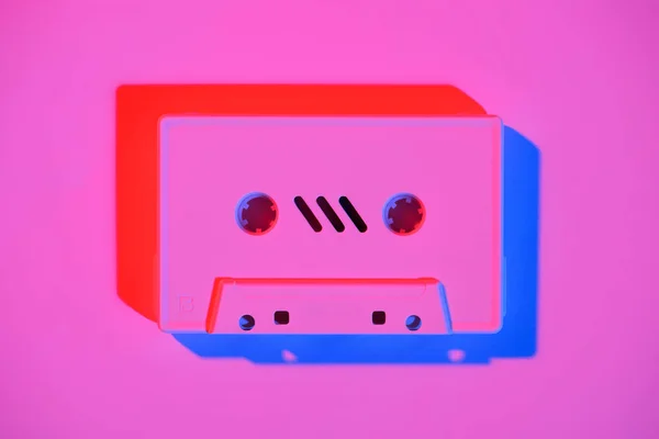 Toned pink picture of retro audio cassette on pink surface — Stock Photo