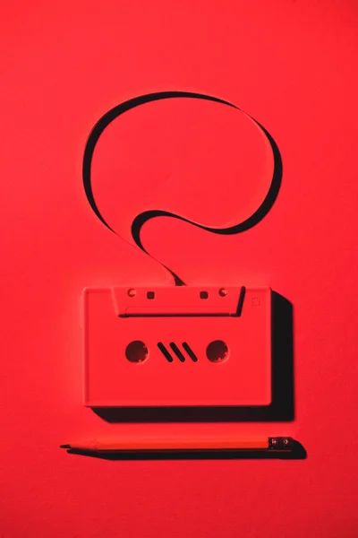 Toned red picture of pencil and retro audio cassette with speech bubble — Stock Photo