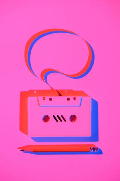 Toned pink picture of pencil and retro audio cassette with speech bubble — Stock Photo
