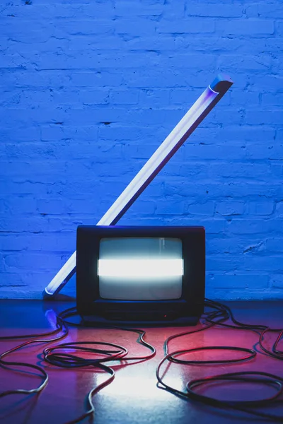 Imagem tonificada de conjunto de tv retro arranjado, cabos e lâmpada com fundo de parede de tijolo — Fotografia de Stock