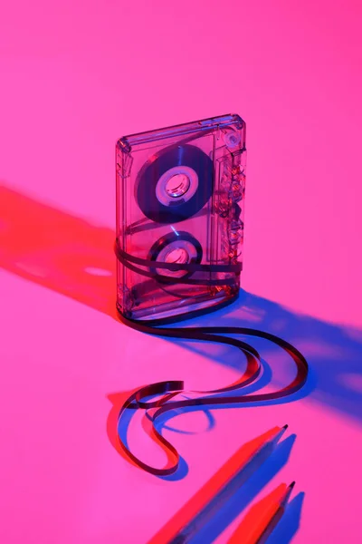 Vista de cerca de cassette de audio retro y lápices sobre fondo rosa - foto de stock