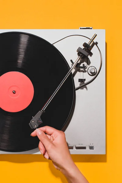 Cropped shot of woman turning on vinyl player isolated on yellow — Stock Photo