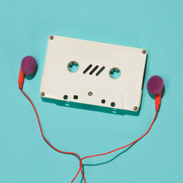 Flat lay com cassete de áudio retro branco e fones de ouvido isolados em azul — Fotografia de Stock