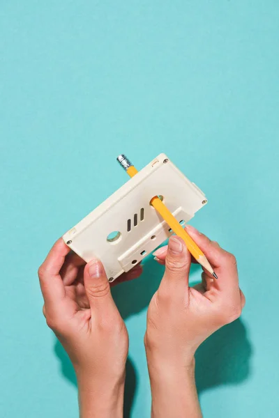 Partial view of woman holding white retro audio cassette and pencil isolated on blue — Stock Photo