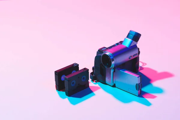 Vista ravvicinata di videocassette organizzate e videocamera digitale su sfondo rosa — Foto stock
