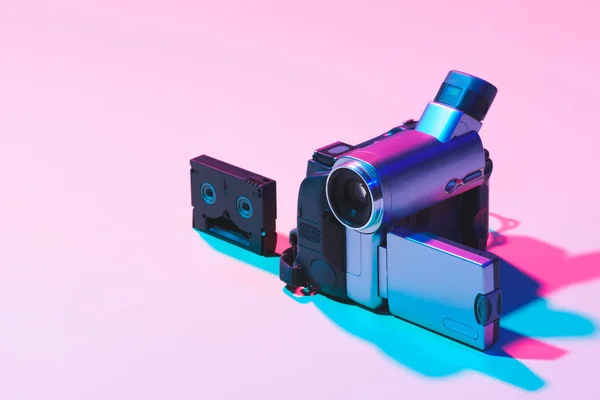 Закрытый вид видеокассеты и цифровой видеокамеры на розовом фоне — стоковое фото