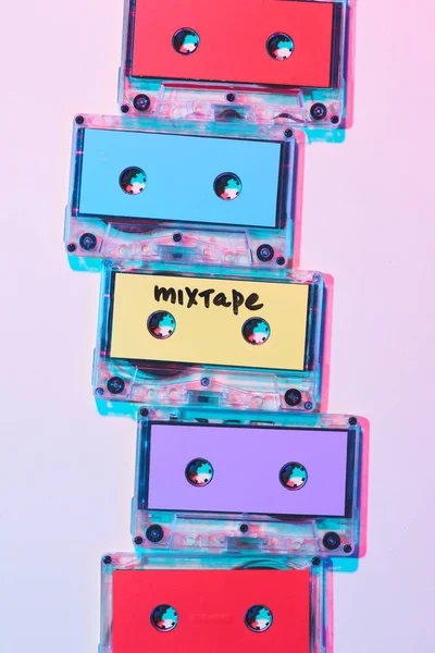 Вид зверху розташовані барвисті аудіокасети з мікстейпом на фіолетовому фоні — стокове фото