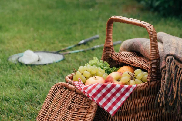 Смачні фрукти в кошику на зеленій траві в парку — стокове фото