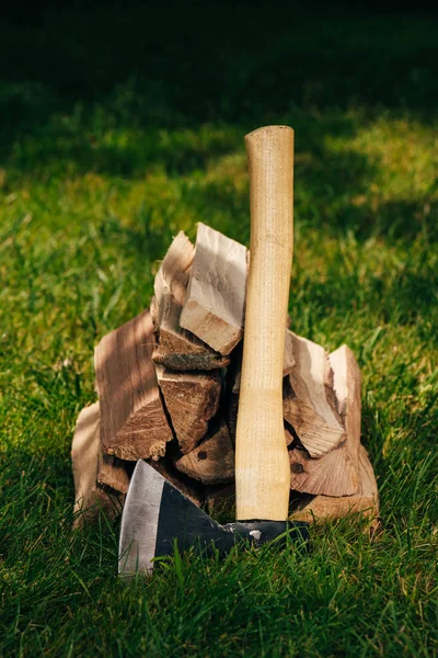 Haufen Brennholz und Axt auf grünem Gras im Park — Stockfoto