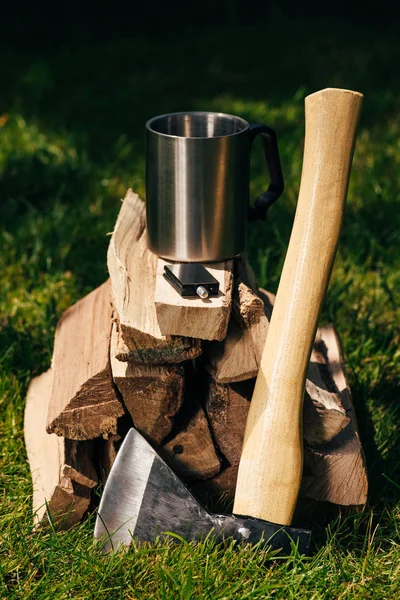 Taza sobre pila de leña sobre hierba verde en el parque - foto de stock