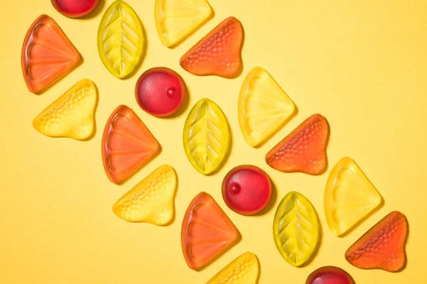 Top view of gummy fruits in row on yellow surface — Stock Photo