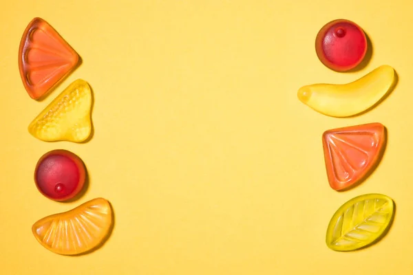 Vue de dessus de divers fruits gommeux colorés sur la surface jaune — Photo de stock