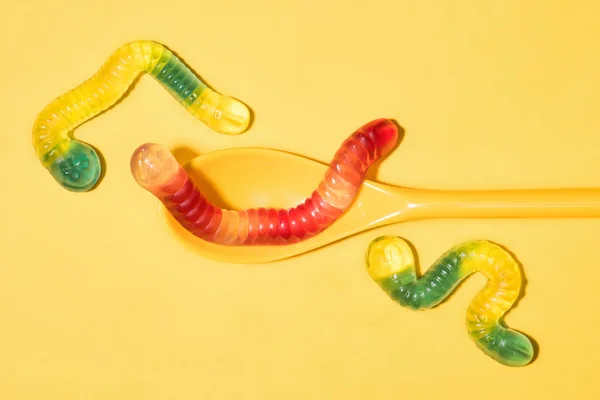 Top view of delicious gummy worms with spoon on yellow — Stock Photo