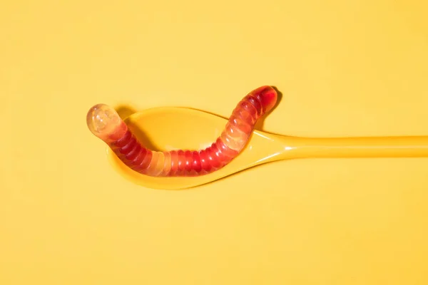 Gummiwurm von oben auf Löffel und auf gelb — Stockfoto